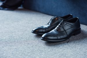 Black male leather shoes placed on carpet floor