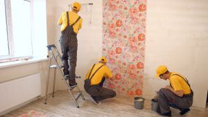 Brigade of builders hang wallpaper in the apartment.