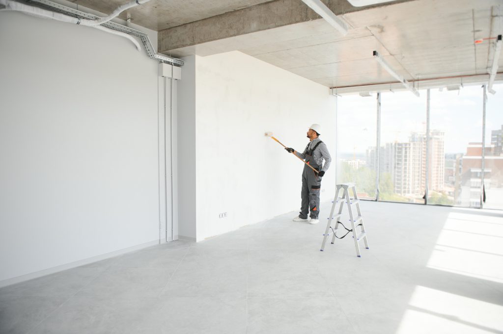 Indian Painter painting the office wall with roller paint