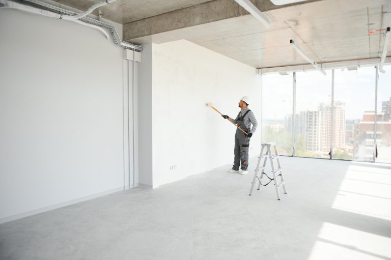 Indian Painter painting the office wall with roller paint
