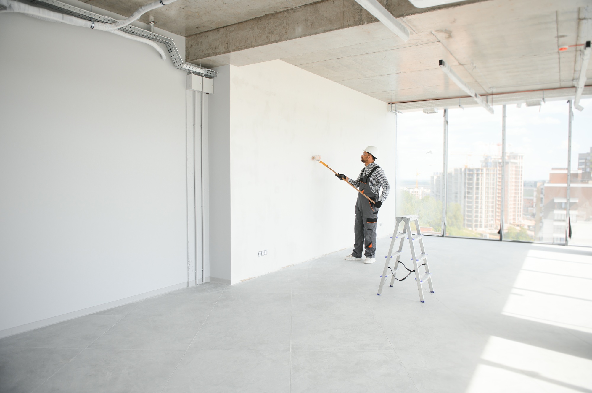 Indian Painter painting the office wall with roller paint